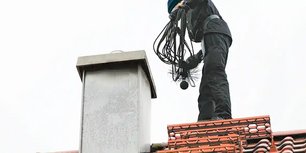 Spazzacamino professionale su tetto durante pulizia canna fumaria